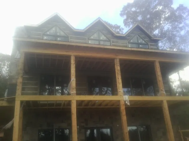 Dormers and porch framing on a large log home under construction — Roof Coating work by our crew in Belfry