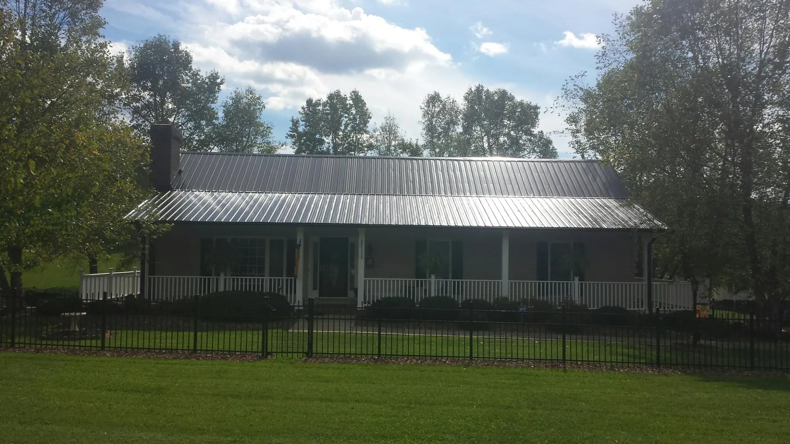 Gray metal roof on a brick ranch with a full width front porch — Gutter Guard Installation work by our crew in Belfry